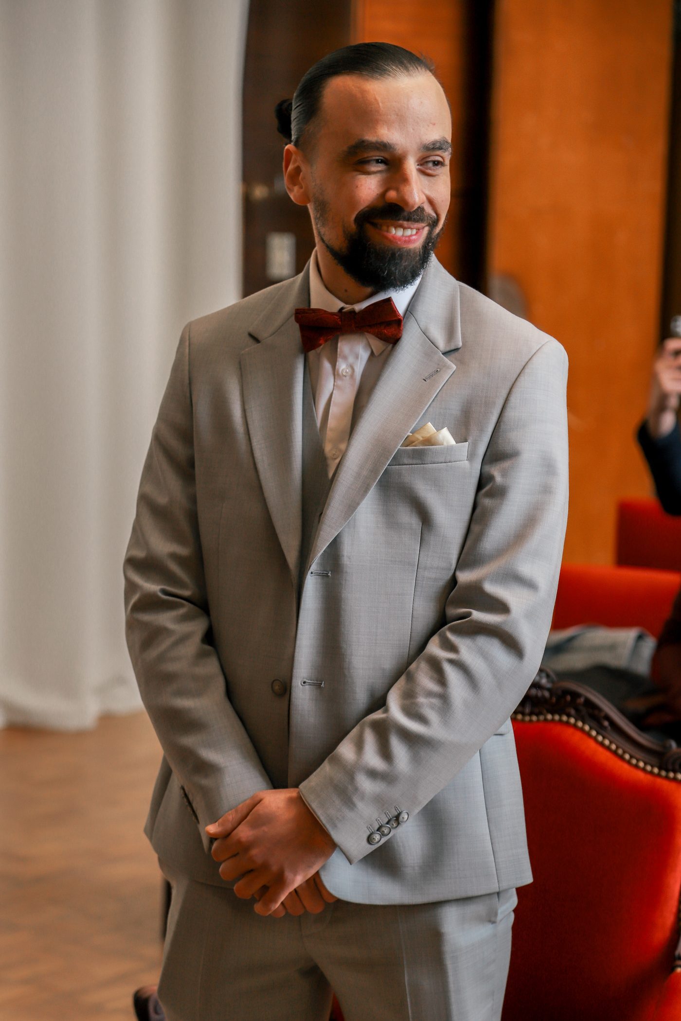 Le marié en costume gris et nœud papillon bordeaux
