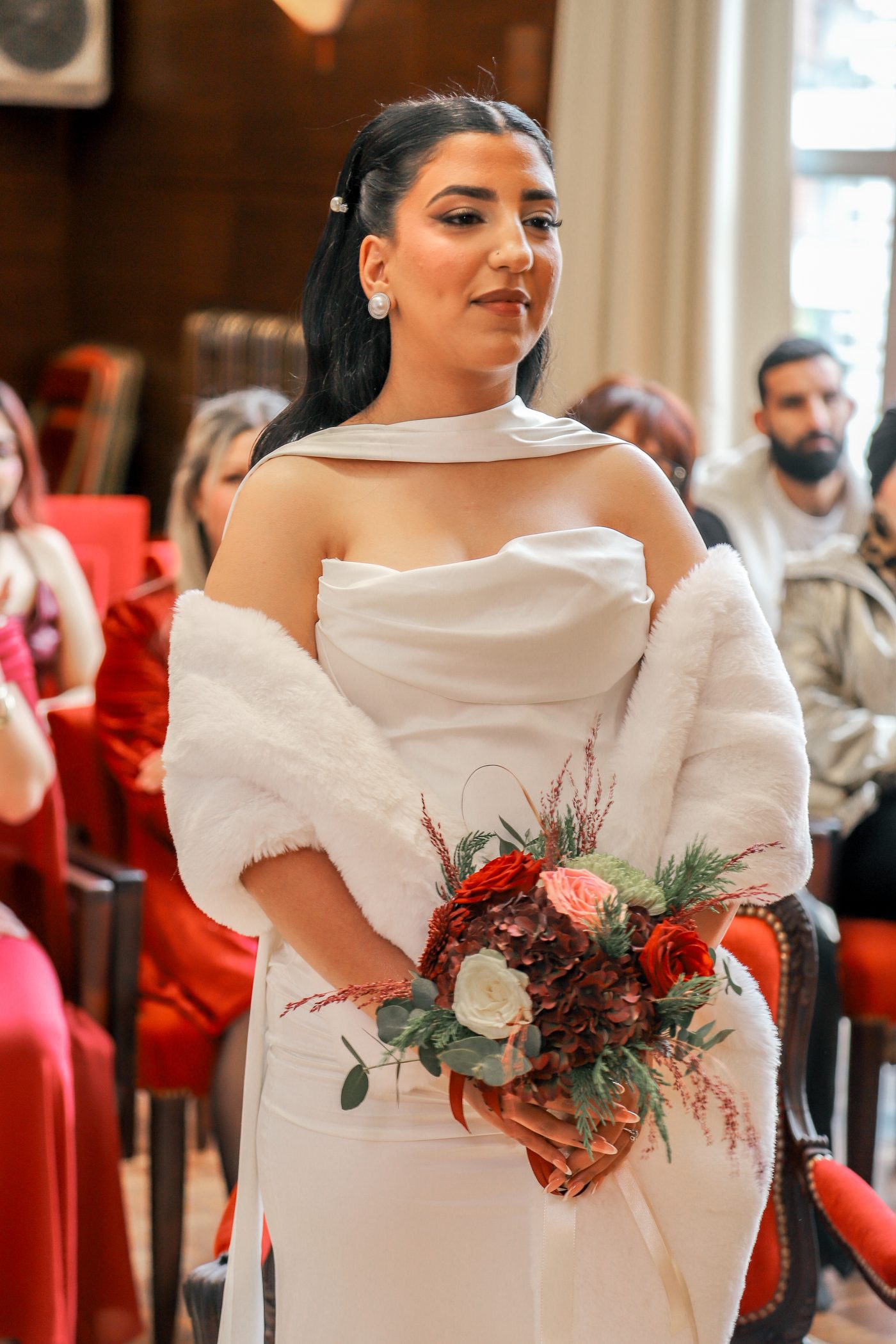 Portrait de la mariée tenant son bouquet rouge pendant la cérémonie