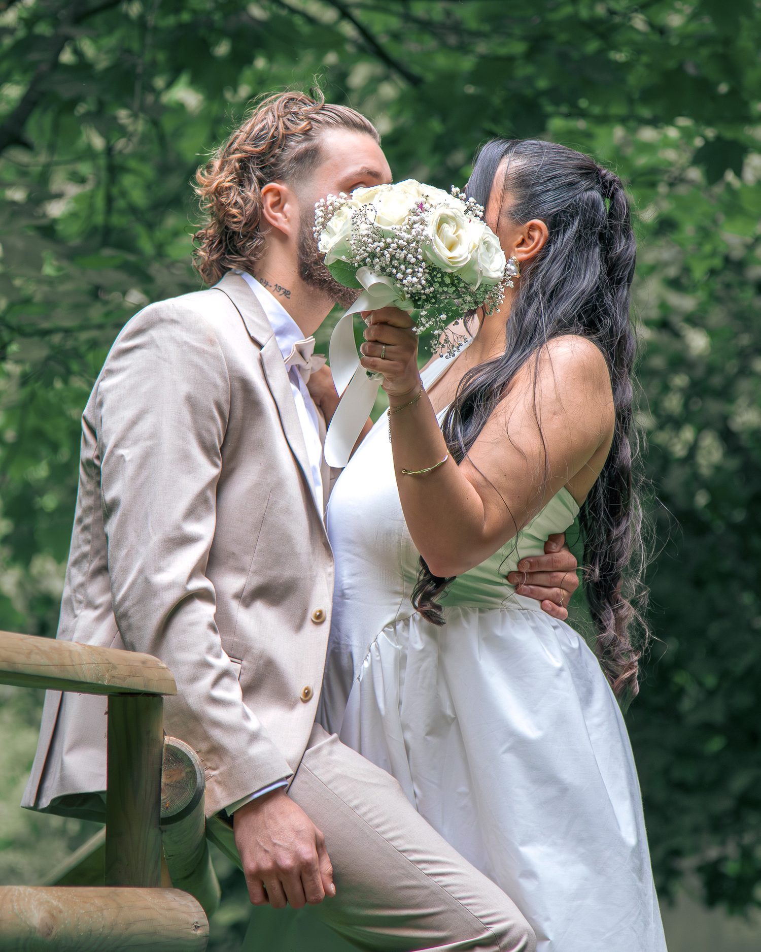 Baiser des mariés caché derrière le bouquet de roses blanches