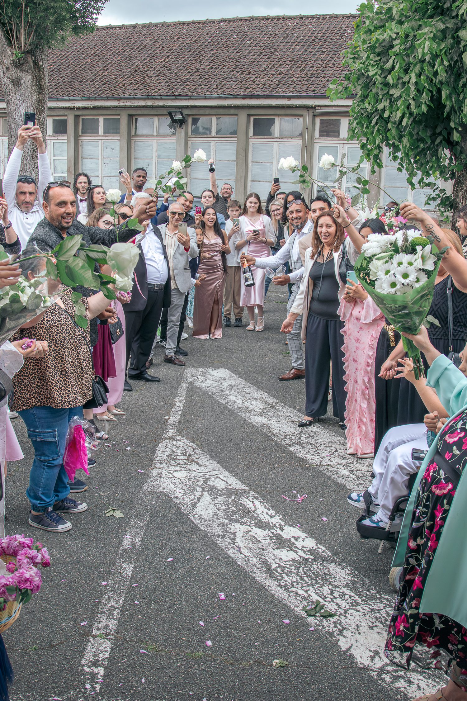 Les invités forment une haie d'honneur avec des roses blanches
