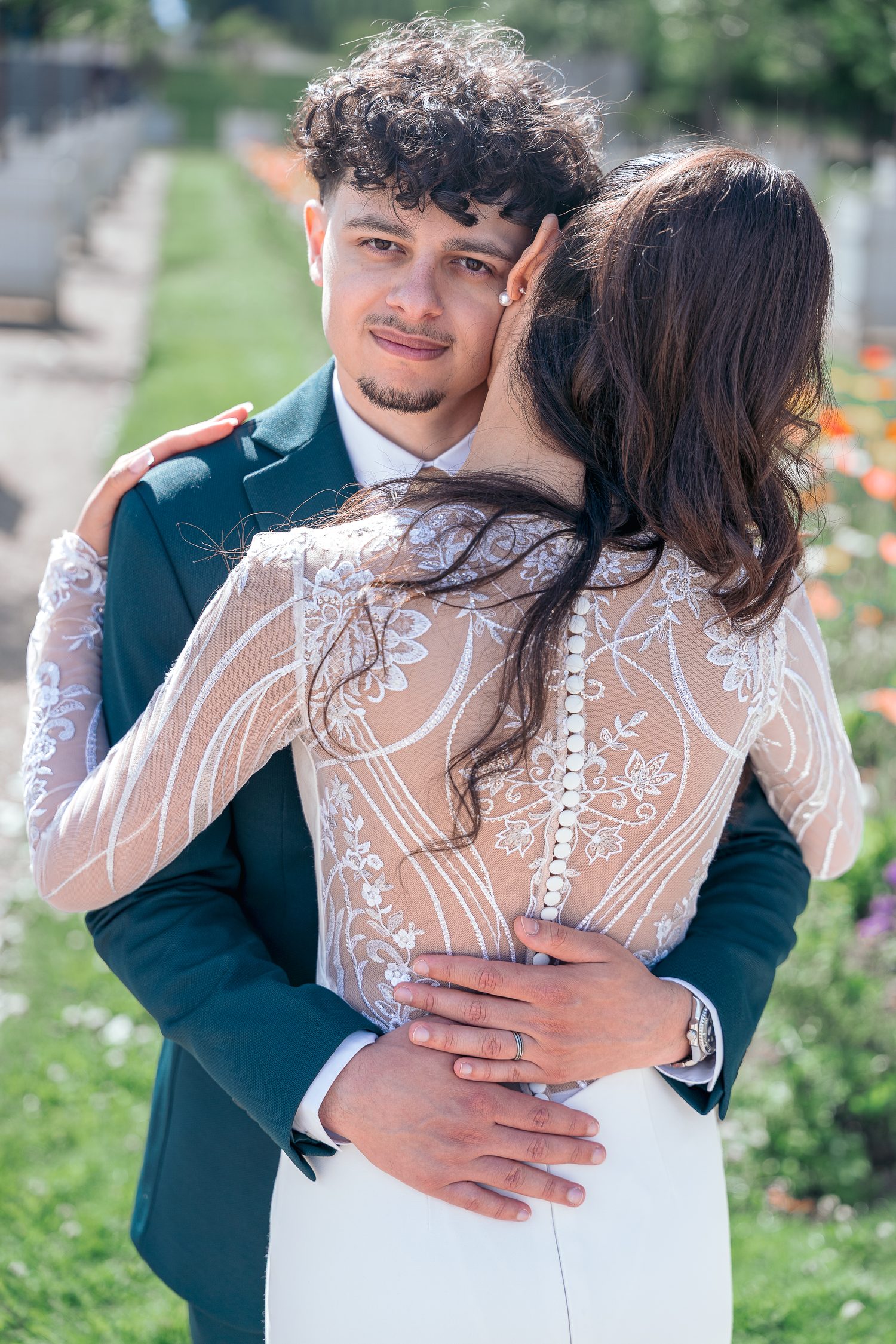 Étreinte des mariés, le dos boutonné de la robe en dentelle face à l'objectif